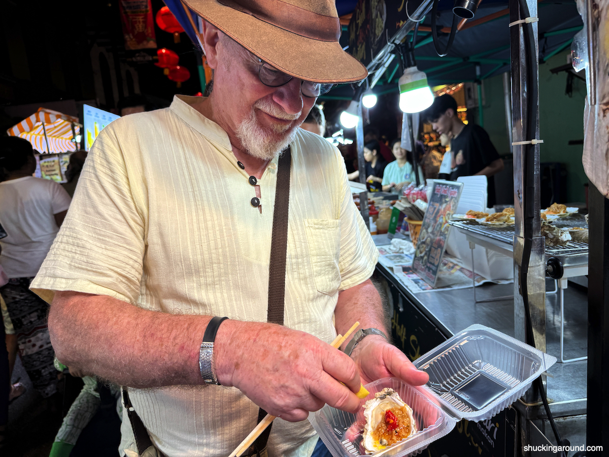 Maurie samples oysters at Jonker Walk Night Market in Melaka, Malaysia.